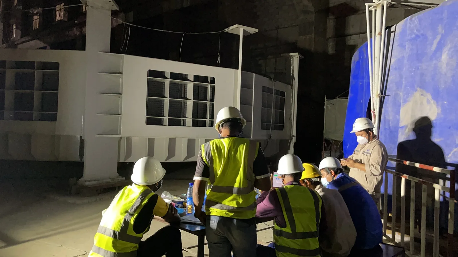 Night commissioning briefing with site engineers in safety gear